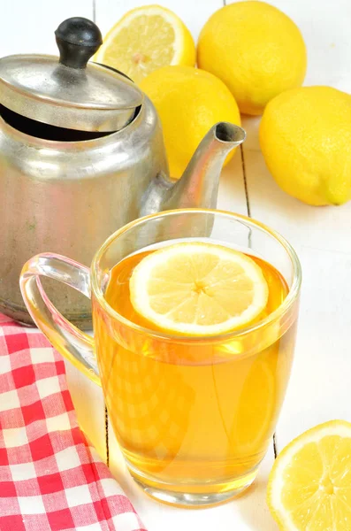 Черный чай с ломтиком лимона в кружке, старый чайник и скатерть — стоковое фото