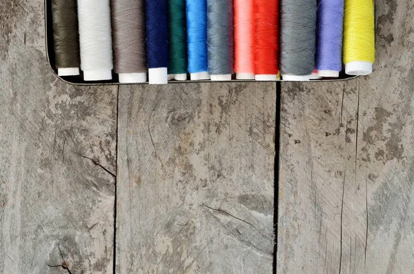 Multi-colored spools of thread on a wooden table — Stock Photo, Image