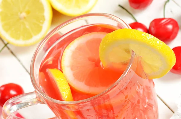 Фруктовый вишневый чай со льдом с ломтиком лимона в кружке и вишней — стоковое фото