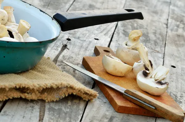 Schneiden von Champignons auf einem hölzernen Schneidebrett und einem Sacktuch — Stockfoto