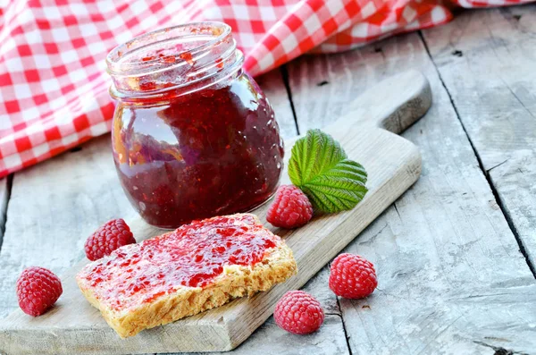 Jar of raspberry jam and fresh raspberries on wooden table — Stock Photo, Image