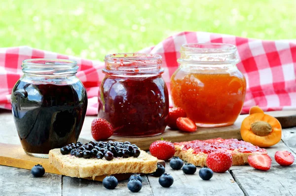 Three Jars Fruit Jam Blueberry Strawberry Apricot Spilled Blueberries Knife — Stock Photo, Image