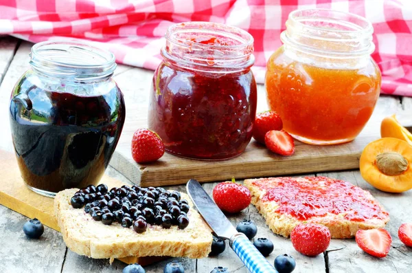 Three Jars Fruit Jam Blueberry Strawberry Apricot Spilled Blueberries Knife — Stock Photo, Image