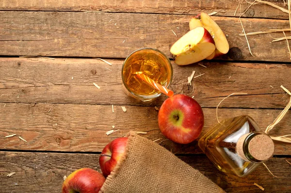 Pemandangan dari atas jus apel buatan sendiri dengan es, apel merah, jerami, masih hidup di atas meja kayu — Stok Foto