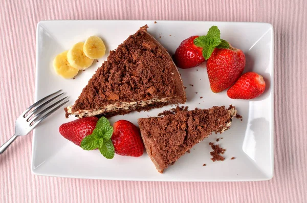 Mole hole cake - homemade cake with whipped cream, banana, strawberries and fresh mint leaves on white decorative shaped plate. Pink place setting. Top view. — Stock Photo, Image