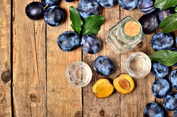 Still-life of fresh garden plums and shots of Slivovice, typical Eastern Europe alcohol plum brandy and bottle. View from above. Vertical photo. — Stock Photo, Image