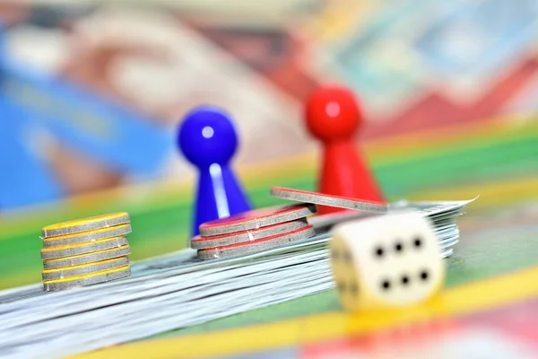 Würfel, rote, blaue Figuren und Chips im Hintergrund auf dem Spielfeld. — Stockfoto