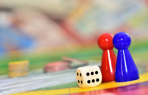 Würfel, blaue, rote Figuren und Chips im Hintergrund auf dem Spielfeld. — Stockfoto