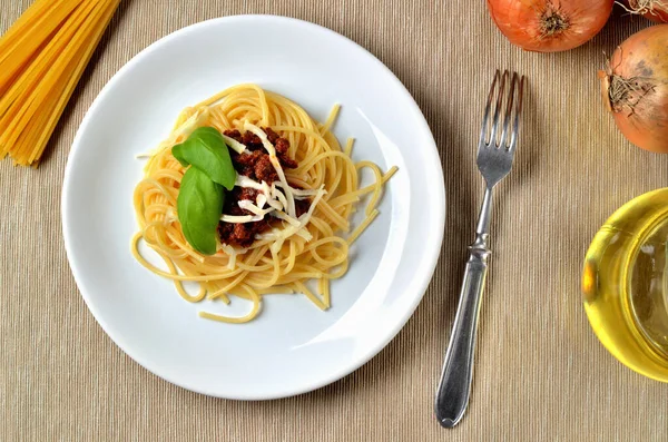 Італійська традиційна паста. Spaghetti bolognese з сиром і базилем. Цибуля, олія і виделка на задньому плані. Краєвид. — стокове фото