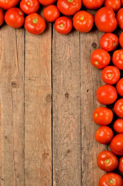 Frische Tomaten auf hölzernem Hintergrund. Draufsicht mit Copyspace. Vertikales Foto. — Stockfoto