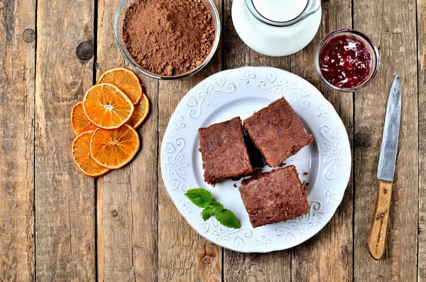 Пряничные пироги, сушеные апельсины, какао-порошок, молоко и джем на белой тарелке и старый нож. Вид сверху . — стоковое фото