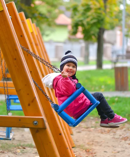 Cute little girl swinging on seesaw on children playground — Stock Photo, Image