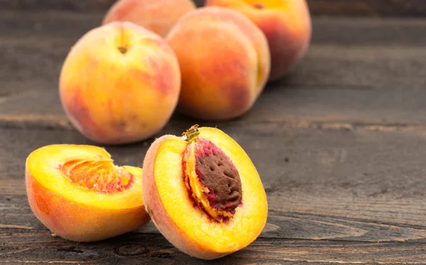 Färska persikor på träbord — Stockfoto