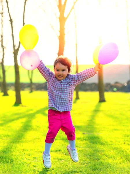 Girl with balloons jumping outdoor, at sunset — ストック写真