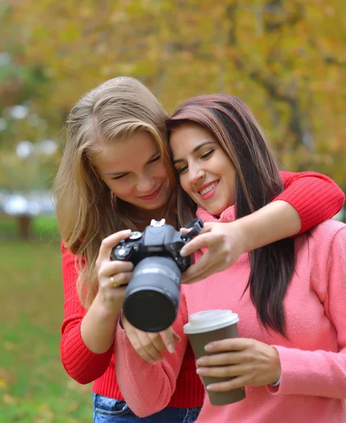 Ritratto di due amiche caucasiche felici che scattano foto con una fotocamera DSLR . — Foto Stock