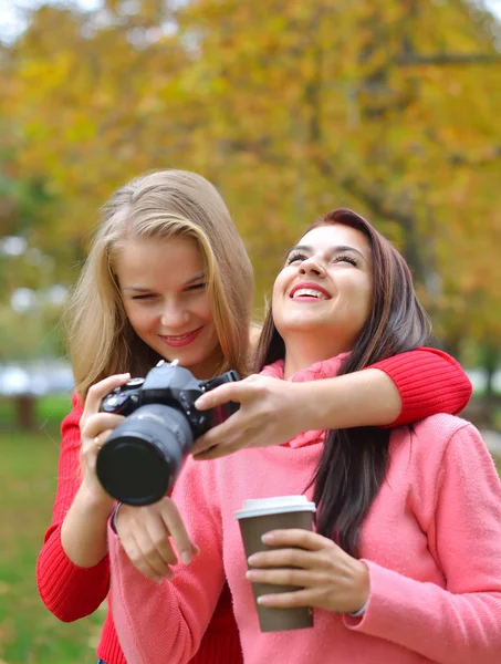 Portrait of two happy female, Caucasian friends taking photos with a DSLR camera. — Stock Photo, Image