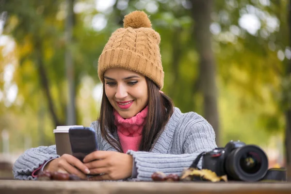 秋の公園で携帯電話でメッセージングの美しい少女 — ストック写真