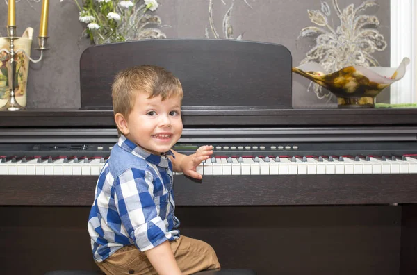 Menino feliz tocando piano em casa — Fotografia de Stock