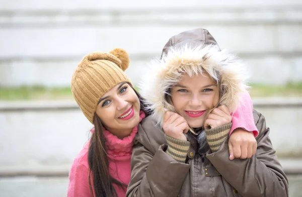 Дві веселі милі дівчата, одна обіймає свого найкращого подругу на відкритому повітрі взимку — стокове фото