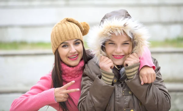 Dos chicas lindas y alegres, una abrazando a su mejor amiga al aire libre en invierno — Foto de Stock