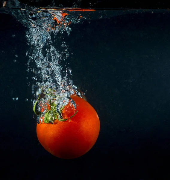 Hög hastighet fotografering tomat plaska i vatten — Stockfoto