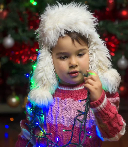 Menina interior no dia de Natal brincando com luzes de árvore — Fotografia de Stock