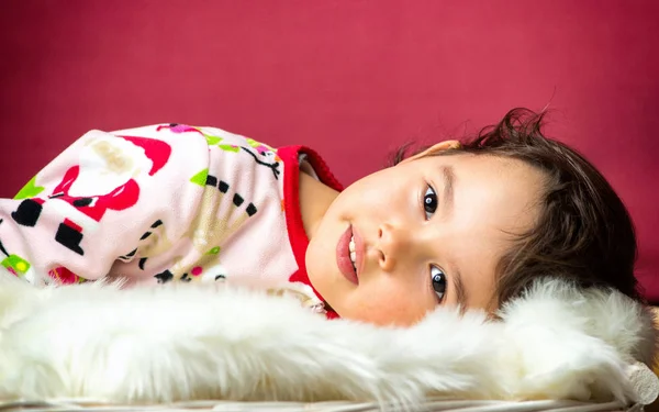 Retrato de menina bonito pouco na cama isolado no vermelho — Fotografia de Stock