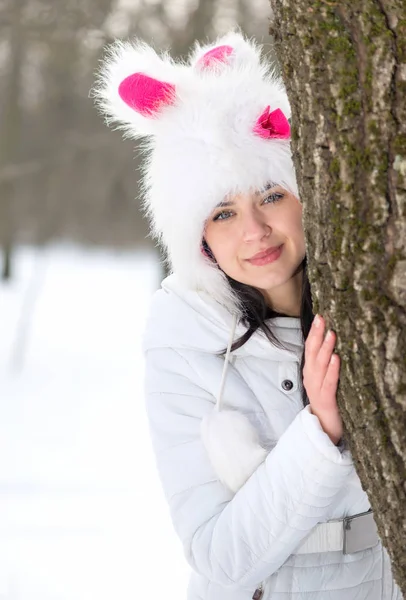 Woman hiding behind tree in winter season — Stock Photo, Image