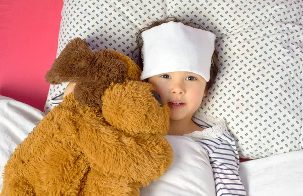 Kleines Mädchen mit Kopfschmerzen im Bett mit Teddybär — Stockfoto