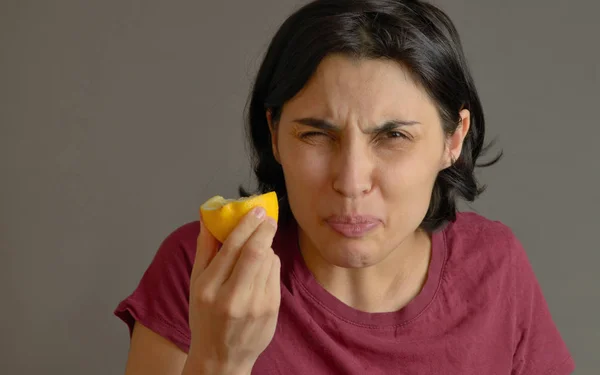 Mulher comendo limão e fazendo caras bobas — Fotografia de Stock