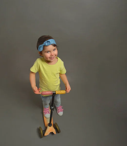 Niña con un scooter aislado sobre gris —  Fotos de Stock