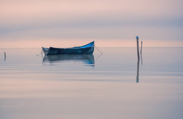 Старая лодка на озере на закате
