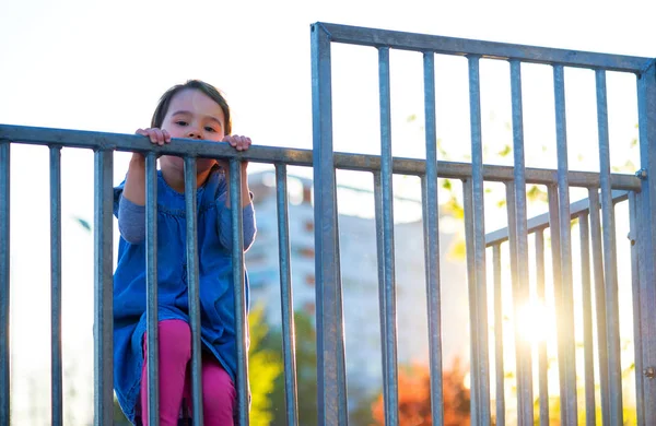 Kleines Mädchen spielt auf Spielplatz mit weißem verschwommenem Parkhintergrund bei Sonnenuntergang — Stockfoto