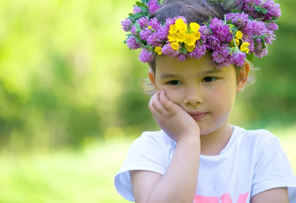 Retrato de una chica alegre con una corona de flores en la cabeza — Foto de Stock