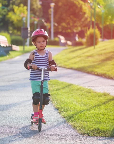 Küçük kız iyi donatılmış bir scooter sürme — Stok fotoğraf