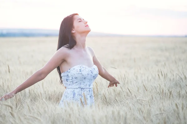 Beautiful woman in summer in wheat field at sunset — Stock Photo, Image