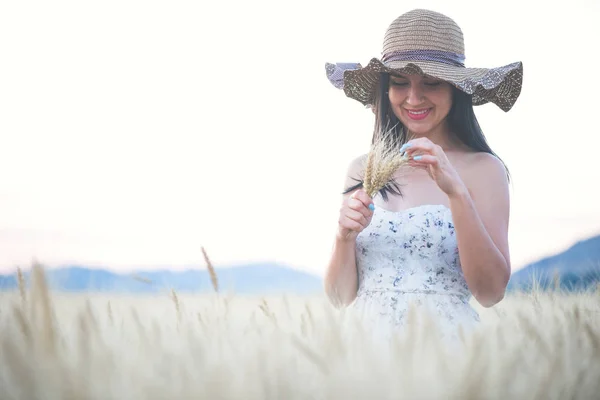 Mooie vrouw met zomer hoed in tarweveld bij zonsondergang — Stockfoto