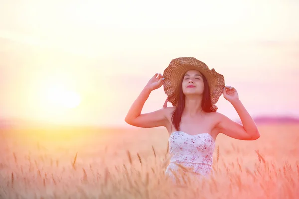 Schöne Frau mit Sommerhut im Weizenfeld bei Sonnenuntergang — Stockfoto