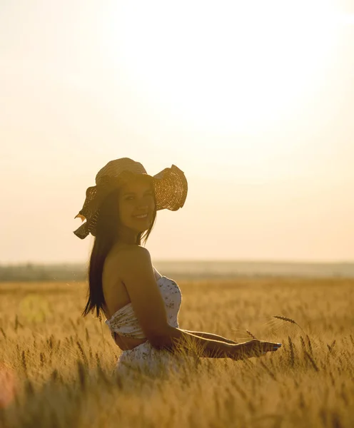 Piękna kobieta z kapelusz lato w polu pszenicy o zachodzie słońca — Zdjęcie stockowe