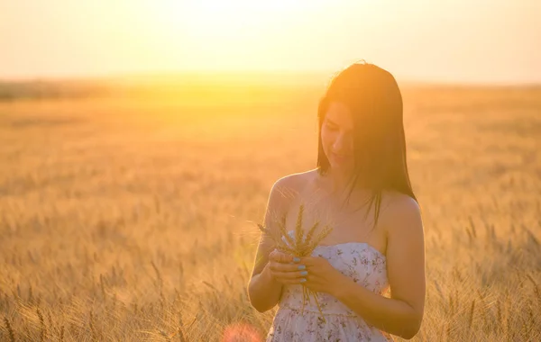 Vacker kvinna med sommar mössa i vetefält i solnedgången — Stockfoto