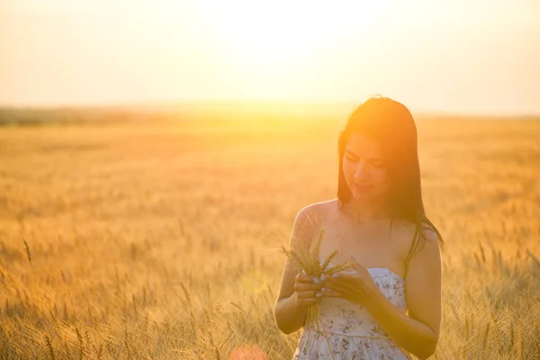 Mooie vrouw met zomer hoed in tarweveld bij zonsondergang — Stockfoto