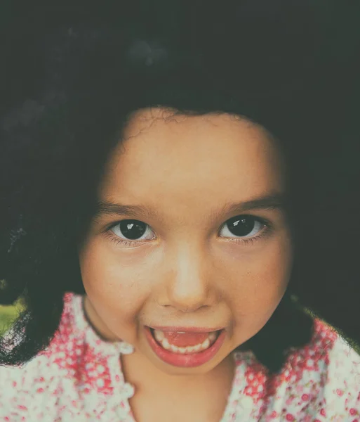 Porträt eines kleinen Mädchens mit großer schwarzer und lächelnder Perücke — Stockfoto