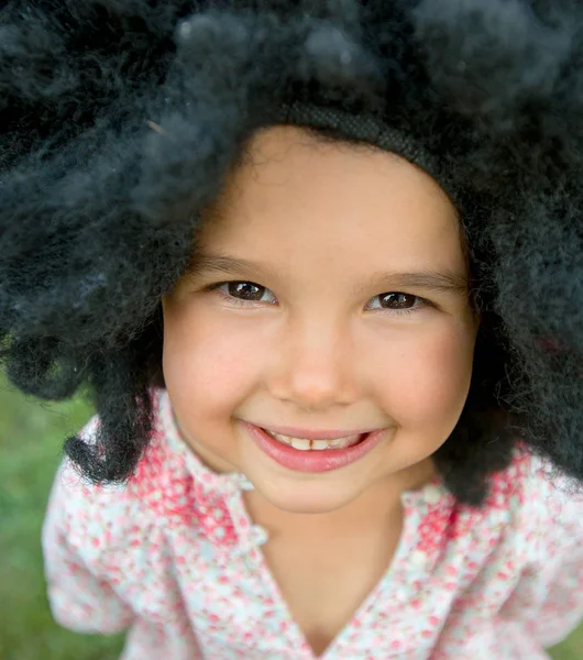 Portret van het meisje draagt een grote zwarte pruik en glimlachen — Stockfoto