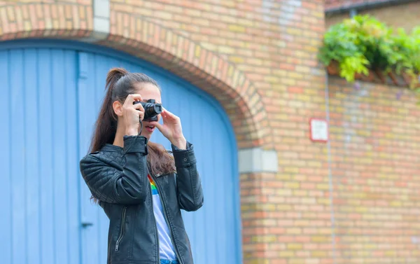 Happy traveler girl making photo of historical building with retro camera on city street — Stock Photo, Image