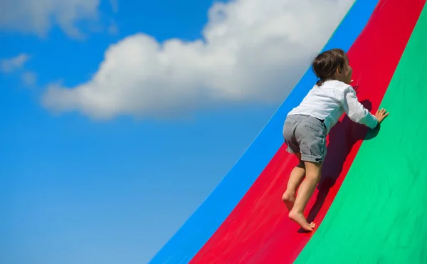 Kleines Mädchen geht auf Regenbogen, auf Spielplatz — Stockfoto