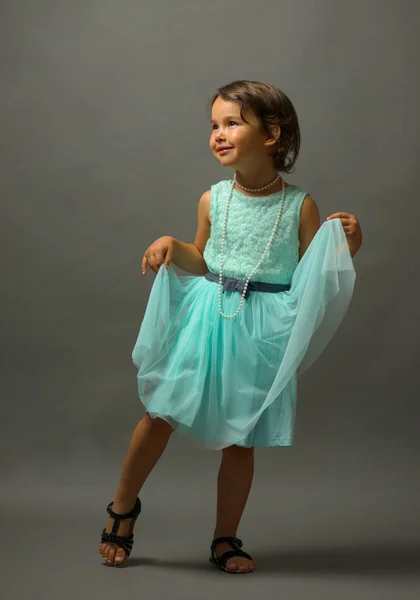 Pequena menina bonito dançando no fundo cinza — Fotografia de Stock