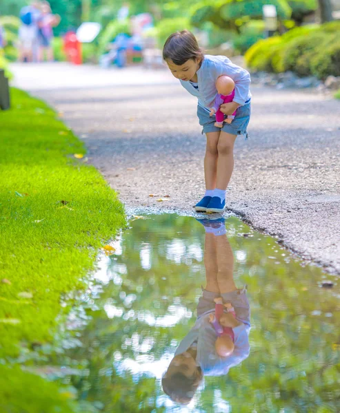 Niña se ve en un charco como un espejo — Foto de Stock