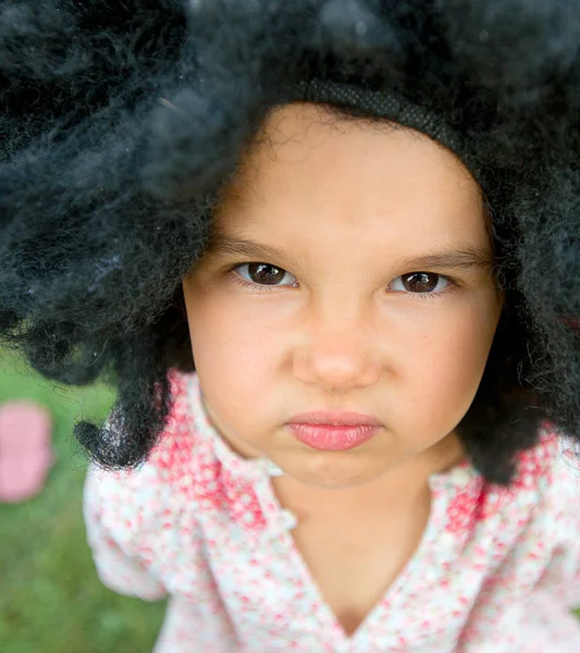 Retrato de menina vestindo uma grande peruca preta — Fotografia de Stock