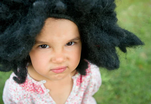 Ritratto di bambina che indossa una grande parrucca nera — Foto Stock