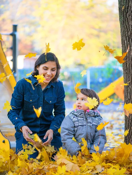 Mutter und ihre kleine Tochter amüsieren sich im Park mit Laub — Stockfoto